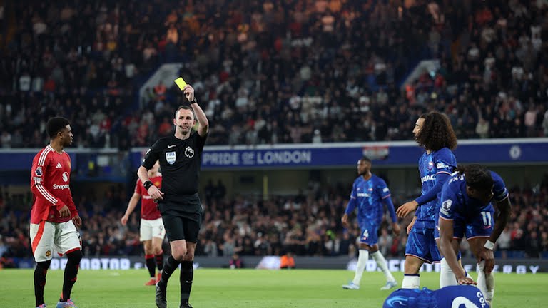 Manchester United's Noussair Mazraoui is shown a yellow card by referee Chris Kavanagh as Chelsea's Levi Colwill reacts on the ground - Photo Credit : Reuters